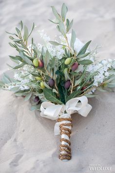 a bridal bouquet with white flowers and greenery tied to it's side