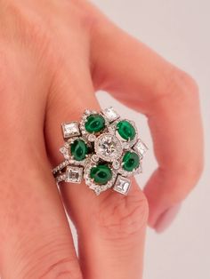 Elegance in Bloom: The Handmade Platinum Entourage Diamond and Cabochon Cut Green Emerald Ring Behold the exquisite charm of this handmade platinum ring, a captivating blend of diamonds and cabochon-cut green emeralds, all woven into a delightful flower and snowflake motif.**Nature's Inspiration**The ring captures the essence of nature's beauty. In its design, you'll find the delicate and harmonious balance of a flower and a snowflake, both elements of nature that have fascinated and inspired artists and admirers for centuries.**Luminous Cabochon Cut Green Emeralds**At the heart of this exquisite creation are five cabochon-cut green emeralds, set to mimic the radiant allure of flower petals. Each emerald, with its alluringly deep green hue, is a testament to the captivating beauty of natur Luxury Green Marquise Diamond Ring, Luxury Green Emerald Ring With Rose Cut Diamonds, Luxury Marquise Emerald Ring With Diamonds, Luxury Platinum Cluster Emerald Ring, Luxury Emerald Cabochon Ring With Diamonds, Exquisite Green Emerald Platinum Ring, Oval Multi-stone Emerald Ring In Platinum, Green Emerald Ring With Rose Cut Diamonds, Exquisite Green Multi-stone Diamond Ring