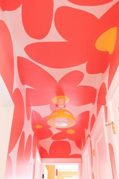 the hallway is painted bright red and has an interesting flower pattern on the ceiling,