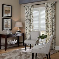 a living room with two chairs and a table in front of the window covered by curtains