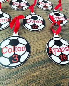 soccer ball ornament with name and number hanging from red ribbon on wooden table