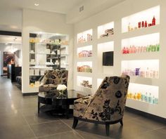 a salon with two chairs and shelves full of hair care products on the wall behind them