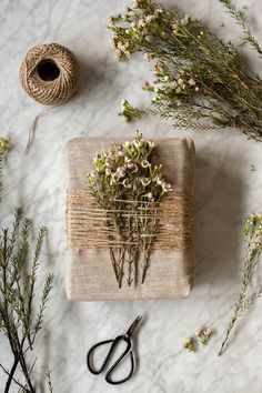 flowers and scissors on a table with twine, spools of twine