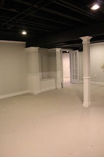 an empty living room with white walls and black ceiling beams in the middle of it