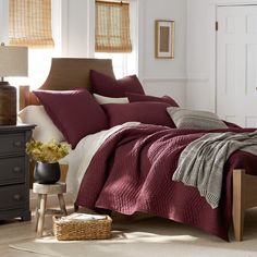 a bedroom with a bed, nightstands and window blinds in shades of burgundy color