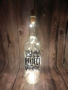 a bottle that has some lights in it on top of a wooden surface with the words life doesn't be perfect to beautiful