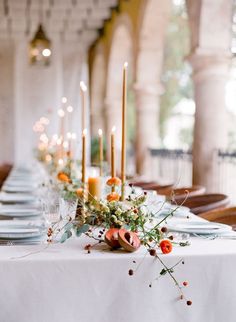 a long table with candles and flowers on it is set up for a formal dinner