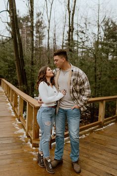 a man and woman standing on a wooden bridge