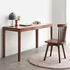 a wooden desk with a chair next to it and a lamp on the wall behind it