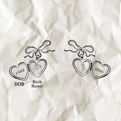 two heart shaped earrings on top of a piece of paper with the words dob and birth