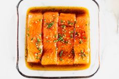 cooked salmon fillets in a glass dish on a marble countertop with seasoning