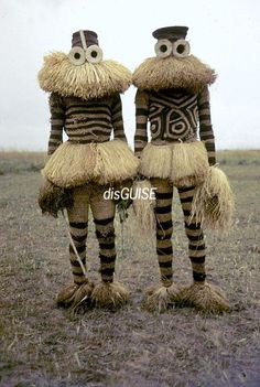 two people dressed in costumes standing next to each other on top of a grass covered field