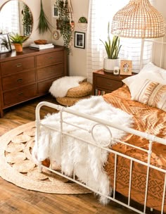 a white metal bed sitting in a bedroom on top of a hard wood floor next to a dresser