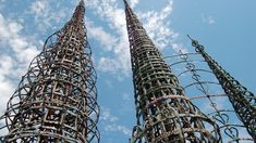 two very tall metal structures with wires on them in the air, against a cloudy blue sky