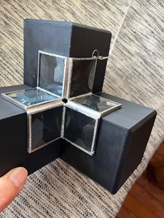 a hand is holding an object made out of black and silver boxes with glass inserts