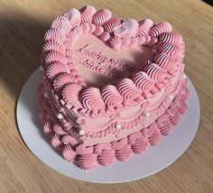 a pink heart shaped cake on a plate with the word love spelled out in it