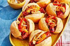 several hot dogs with toppings on a yellow platter