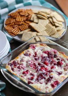 a table with crackers, cranberry cheese dip and other snacks on it