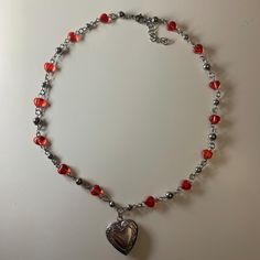 This necklace features silver beads and small red heart-shaped charms. It is accented with a silver heart-shaped locket at the center, giving it a romantic and elegant look. The necklace has an adjustable clasp, combining simplicity with a sweet, vintage-inspired design. Heart Locket Necklace, Heart Locket, Vintage Inspired Design, Locket Necklace, A Romantic, Silver Heart, Red Heart, Silver Beads, Romania