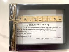 a scrabble frame with the word principals written on it and a string attached to it