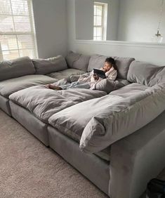 a person laying on top of a couch with a book in their hand and looking at it