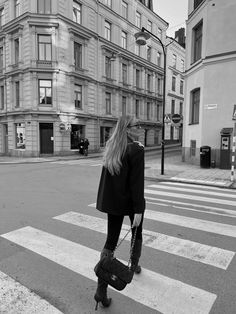 a woman is standing on the cross walk