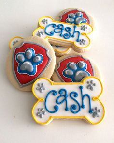 three decorated cookies with the words cash and dog's paw on them, sitting next to each other