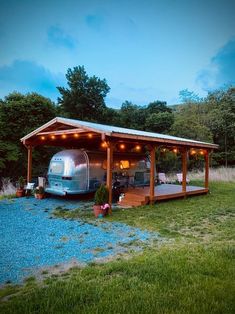 an rv is parked in the grass under a covered area with lights on it's roof