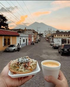 a person holding up a plate with food on it and a cup of coffee in front of them