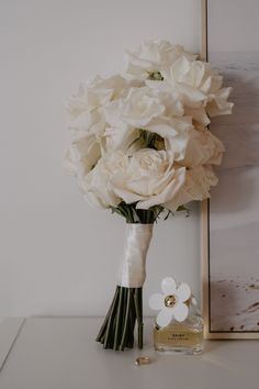 a bouquet of white flowers sitting on top of a table next to a perfume bottle