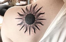 a woman's shoulder with a sun tattoo on it