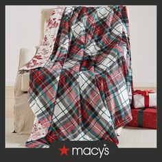 a red and green plaid blanket sitting on top of a white couch next to presents