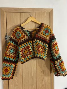 a crocheted sweater hanging on a wooden door