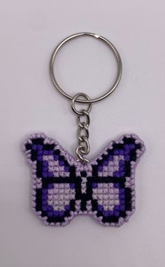 a purple and black butterfly shaped keychain on a white surface with a metal ring