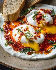 an image of eggs on bread with tomato sauce and herbs in the middle for garnish