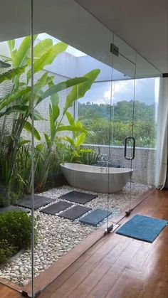 a bathroom with glass walls and wooden flooring next to a bathtub in the middle