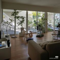 a living room filled with lots of furniture and plants on top of wooden flooring