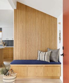 a wooden bench sitting in the middle of a living room next to a wall with vertical slats on it