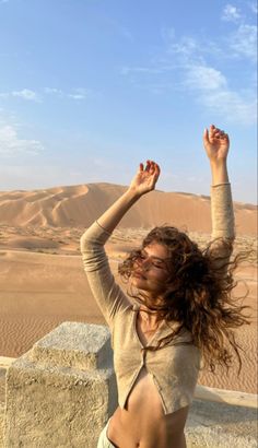 a woman standing in the desert with her arms up