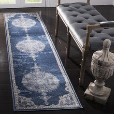 a blue and white runner rug in front of a chair with a vase on the floor