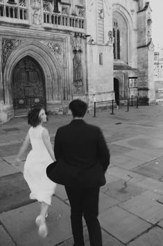 a man and woman are walking in front of an old building