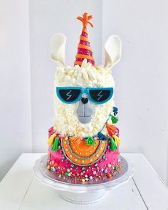 a birthday cake with a llama wearing sunglasses and a party hat on it's head