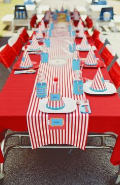 a long table set up with red and white striped cloths, plates and napkins