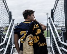 a young man wearing a football jersey is walking up the stairs with his hand on his shoulder