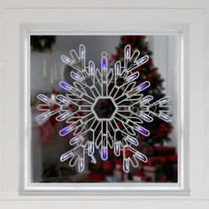 a snowflake is seen through a window in front of a decorated christmas tree