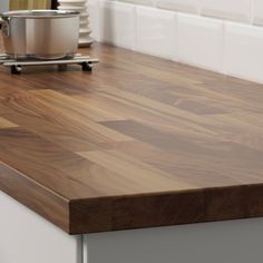 a wooden counter top in a kitchen next to a pot and pan on the stove