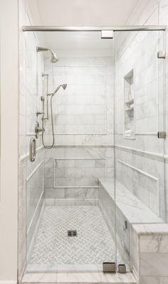 a walk in shower sitting next to a white tiled wall and floor with glass doors