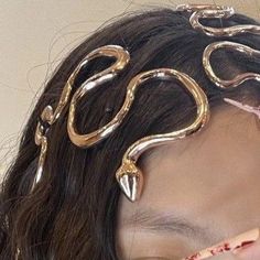 a woman with gold hair clips on her head and makeup brushes in her mouth,