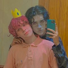 two people are taking a selfie in front of a mirror with one person wearing a crown on his head