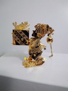 a gold and black object sitting on top of a white table next to a flower